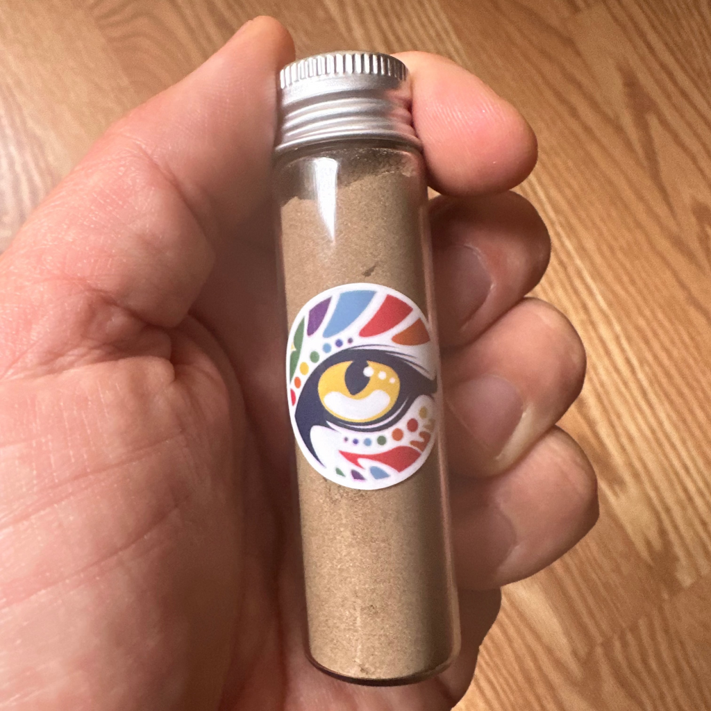 Hand holding a small cylindrical container with a colorful logo on a wooden surface